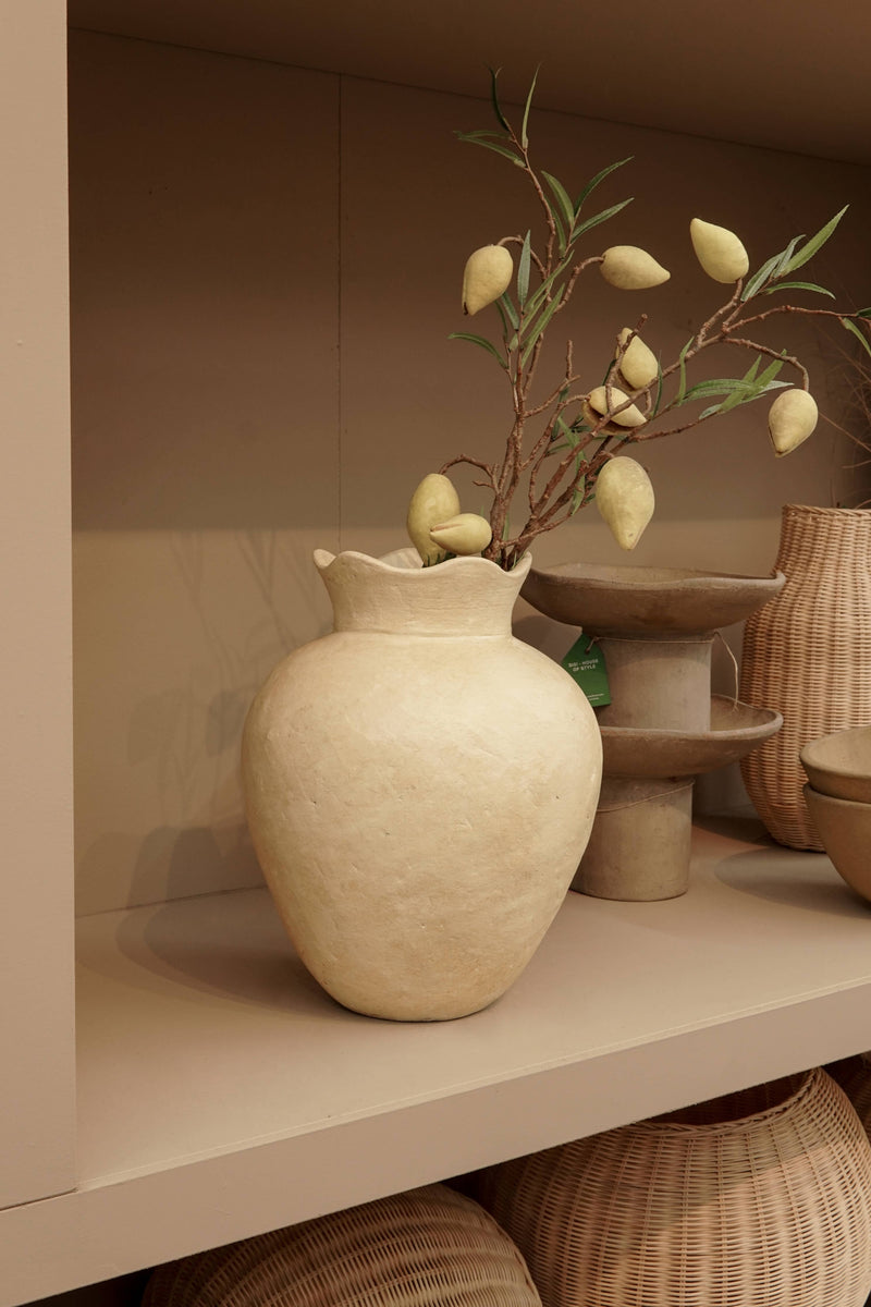 Handgefertigte terrakotta-vase „Mara“ in warmem Gelb-Beige mit Zweigen und dekorativen Elementen auf einem Regal.